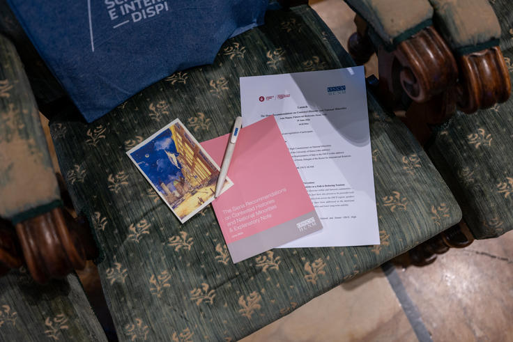Brochure, postcard, and pen on a vintage floral-patterned armchair.