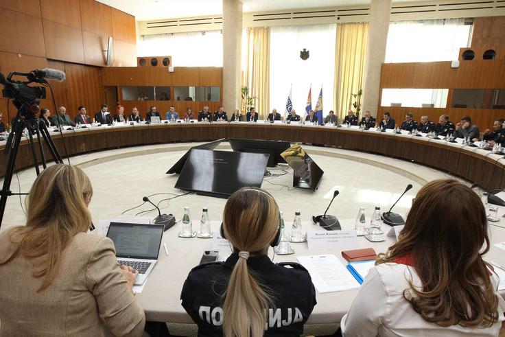 A large conference room with people seated around a circular table, engaged in a meeting.