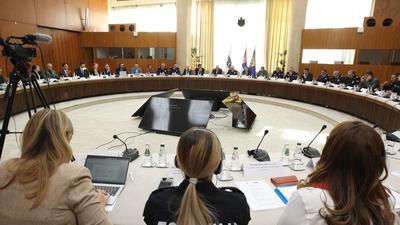 A large conference room with people seated around a circular table, engaged in a meeting.